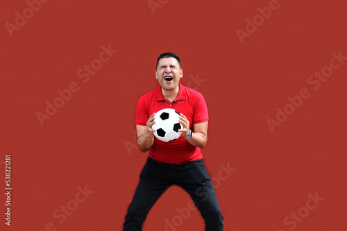 Fototapeta Naklejka Na Ścianę i Meble -  Latino adult man plays with a soccer ball very excited that he is going to see the World Cup and wants to see his team win