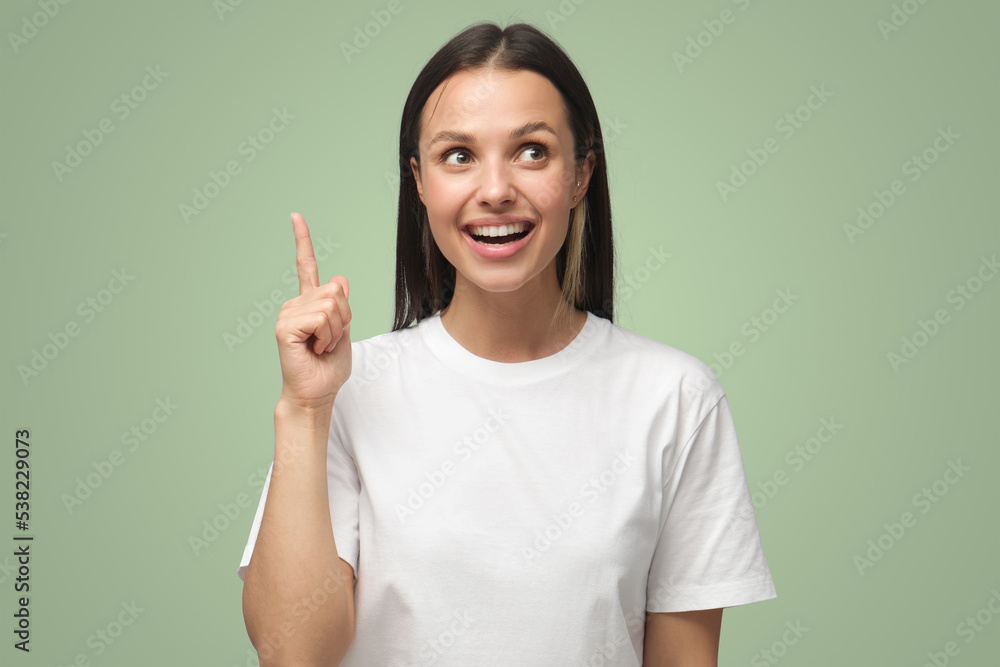 Woman keeping finger pointed upwards, showing something above head with index finger Woman keeping finger pointed upwards, showing something above head with index finger