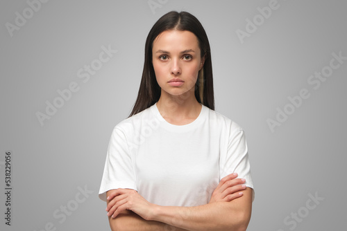 Canvas Print European female standing with arms crossed showing doubt and mistrust on gray ba
