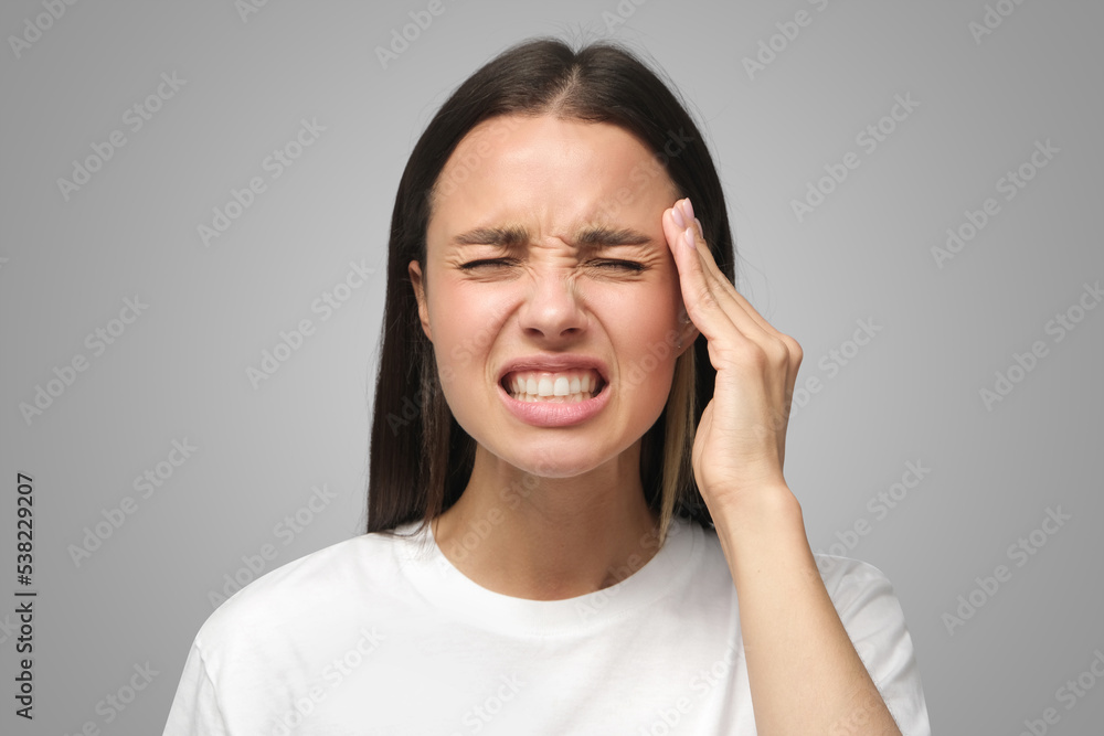 Woman suffering from headache, pressing fingers to temples, closing eyes to relieve pain