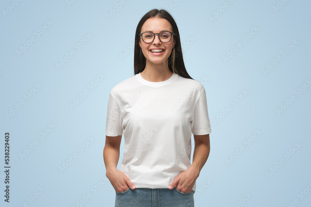 © Damir Khabirov - Laughing woman with hands in pockets, wearing blank white t-shirt with copy space, isolated on blue © Damir Khabirov - Laughing woman with hands in pockets, wearing blank white t-shirt with copy space, isolated on blue