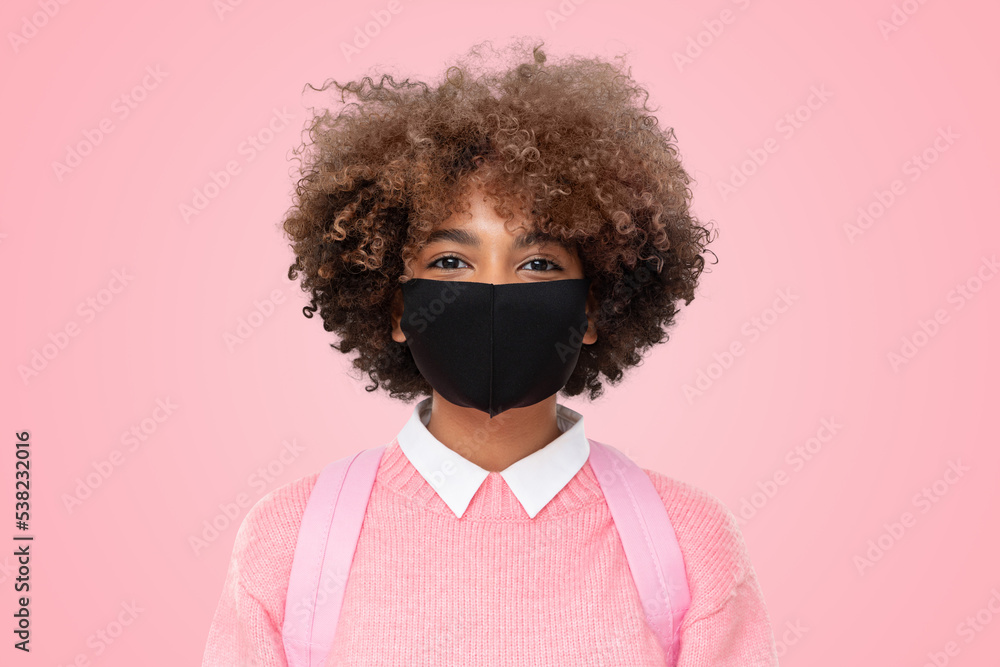 Smiling african american school student girl student with curly afro hair wearing black cotton mask Smiling african american school student girl student with curly afro hair wearing black cotton mask