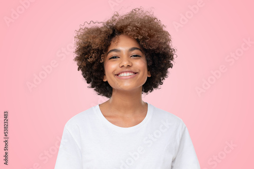 Portrait of laughing african girl in white t-shirt looking at camera on pink background