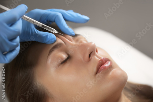 Beautiful woman getting facial injection in salon, closeup