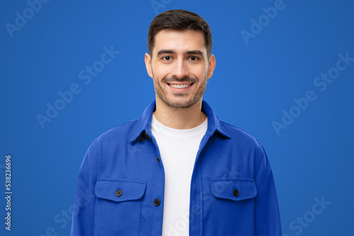 Portrait of smiling young man in blue workwear shirt on blue background