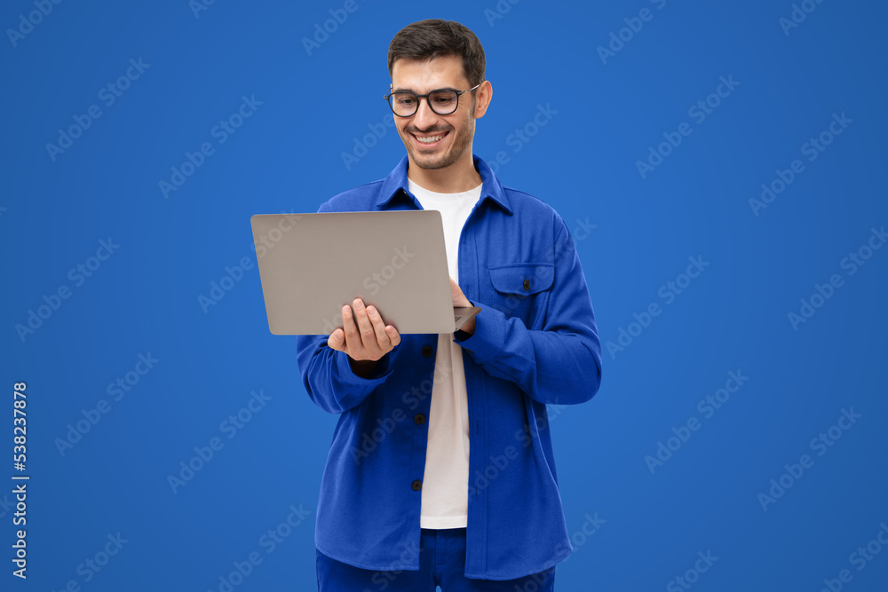 Young man holding laptop surfing, browsing online, typing message or watching movie Young man holding laptop surfing, browsing online, typing message or watching movie