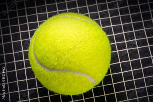 Tennis ball isolated on tennis racquet background, Yellow Tennis ball sports equipment on black background.