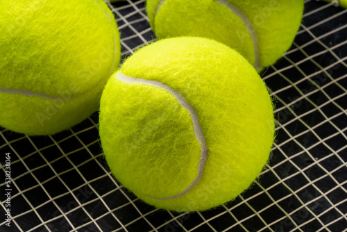 Tennis ball isolated on tennis racquet background, Yellow Tennis ball sports equipment on black background.