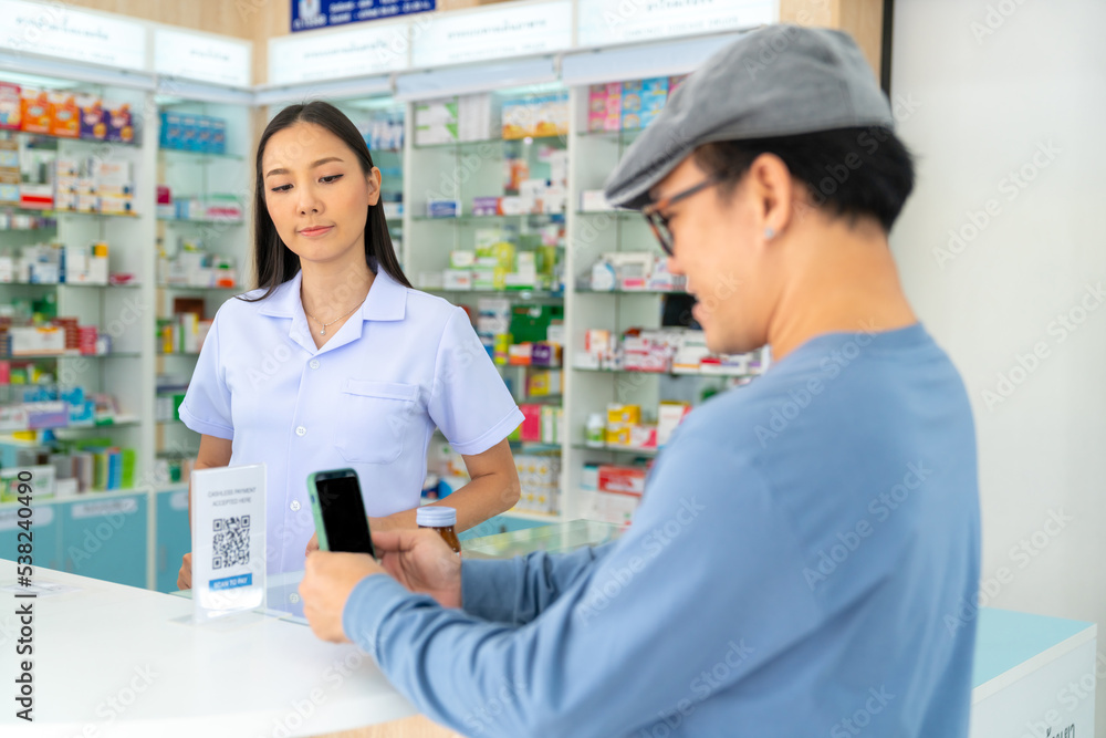 Medical pharmacy and contactless payment concept. Asian man patient customer using mobile phone scan QR code on counter making online banking payment buying medicine, drugs and supplement in drugstore