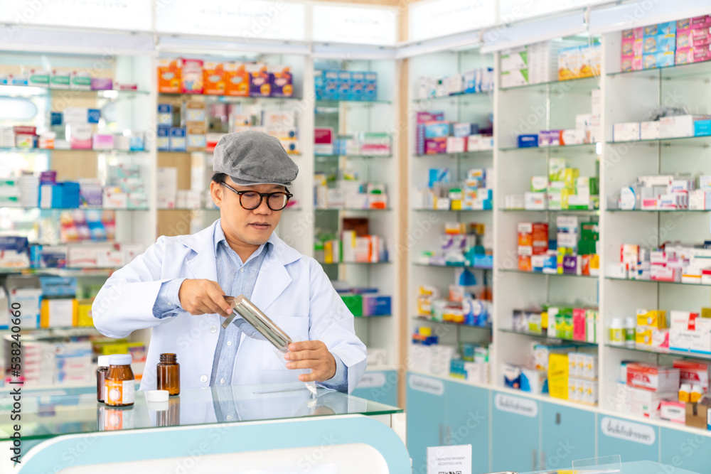 Medical pharmacy and healthcare providers concept. Asian man professional pharmacist counting drug pills on counting trays by hospital prescriptions on counter to patient customer in modern pharmacy. Medical pharmacy and healthcare providers concept. Asian man professional pharmacist counting drug pills on counting trays by hospital prescriptions on counter to patient customer in modern pharmacy.