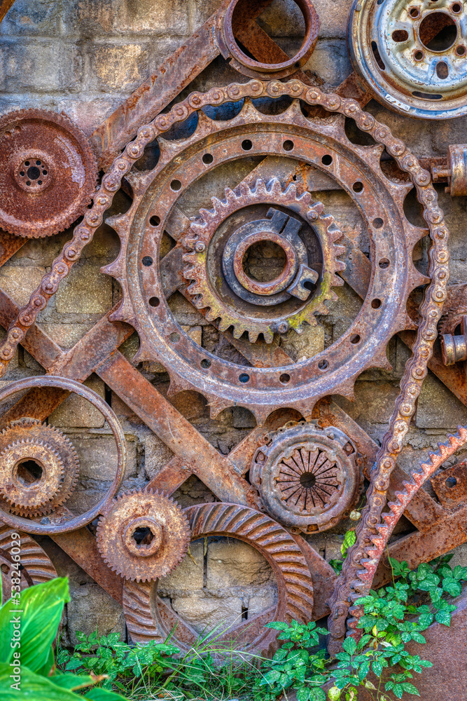 old rusty gear wheels with green plant