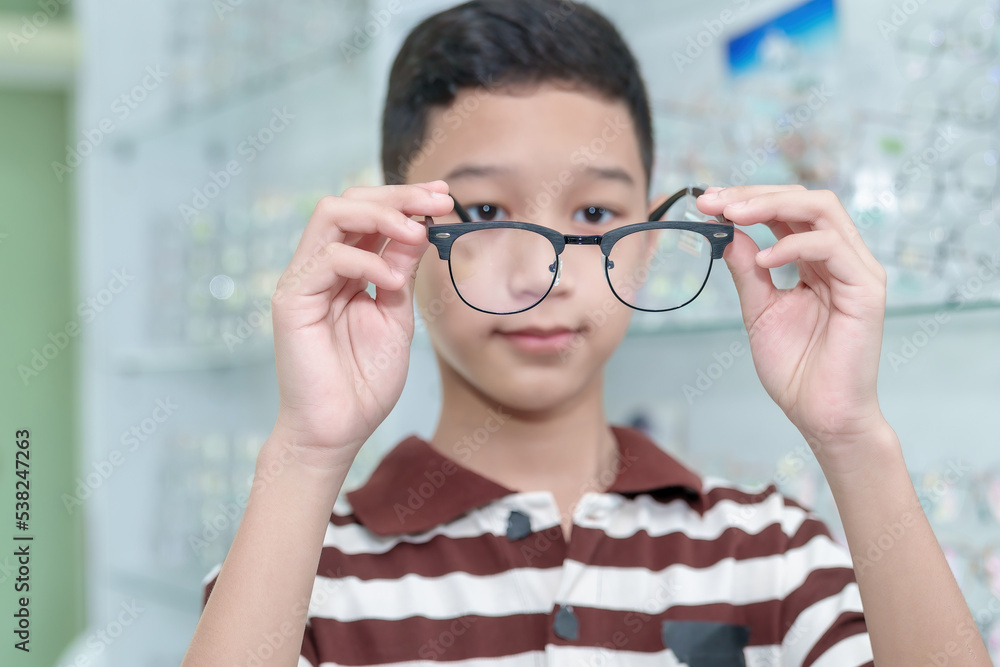 Boy choosing eyeglass frames in an eyeglass assembly shop Boy choosing eyeglass frames in an eyeglass assembly shop