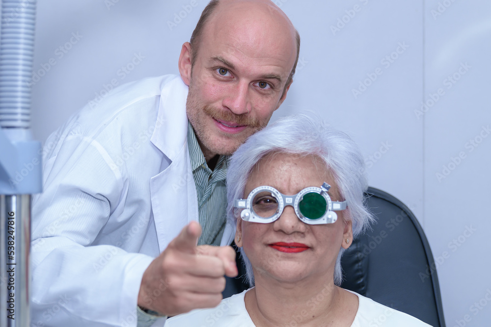 Attractive male ophthalmologist is checking eye vision of middle aged woman in modern clinic, doctors and ophthalmology clinic patients.