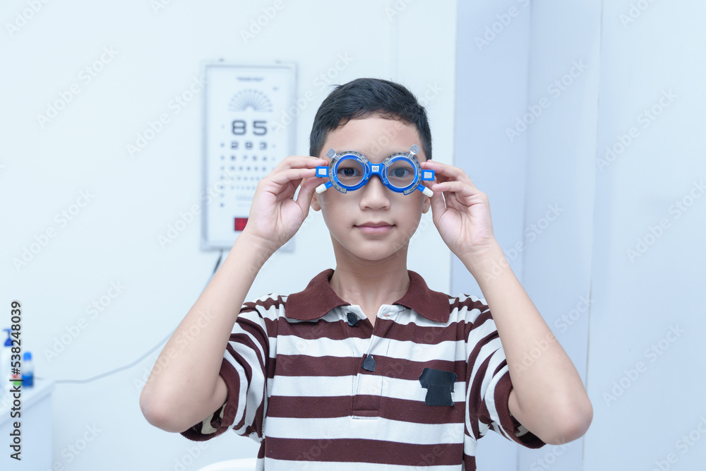 Smiling boy in glasses examining eyesight at a pediatric ophthalmologist with grandma to support in modern clinic, doctors and ophthalmology clinic patients. Smiling boy in glasses examining eyesight at a pediatric ophthalmologist with grandma to support in modern clinic, doctors and ophthalmology clinic patients.