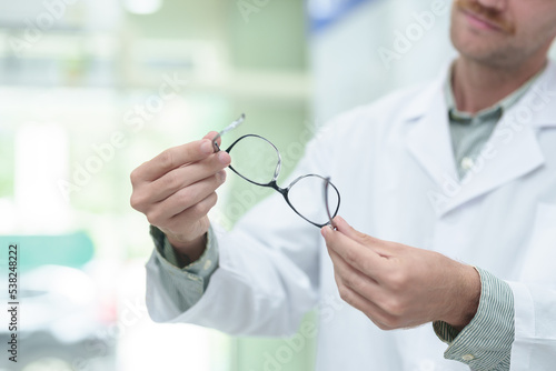 male ophthalmologist with eyeglasses in clinic, closeup. Space for text