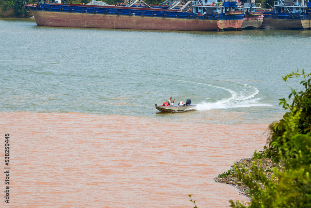 Obraz premium A sailor drives a speedboat at the confluence of two rivers