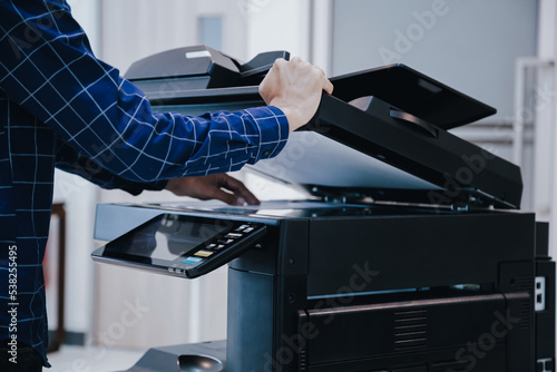 Copier printer, Close up hand office man press copy button on panel to using the copier or photocopier machine for scanning document printing a sheet paper. photo