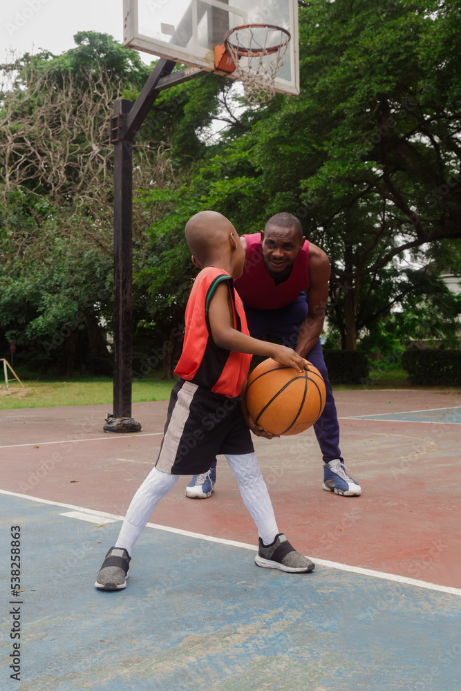 Father and son with basketball on court