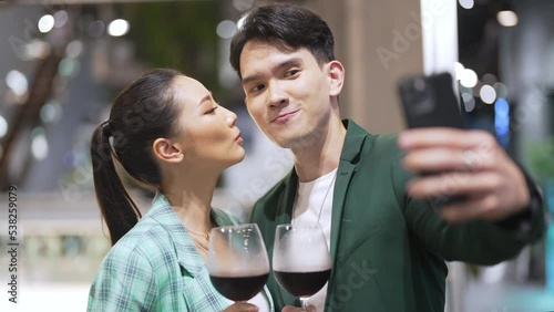 4K Happy Asian couple celebrating holiday event at luxury restaurant in the city at night. Man and woman enjoy city lifestyle having dinner and drinking wine together at bar terrace on travel vacation