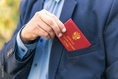 Man in blue suit shows red ID card or pass. An important untouchable employee of ministry is driving a car. state Duma deputy of Russia inscription on the red document. Parliamentary immunity concept.