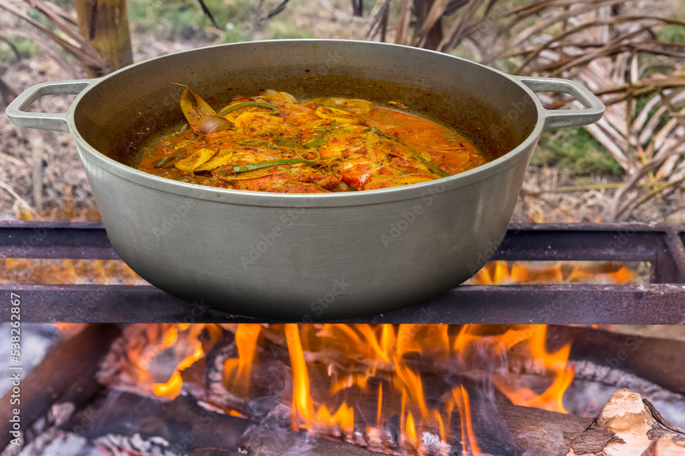 Cari de poissons rouges dans marmite créole sur feu de bois foto de Stock Adobe Stock