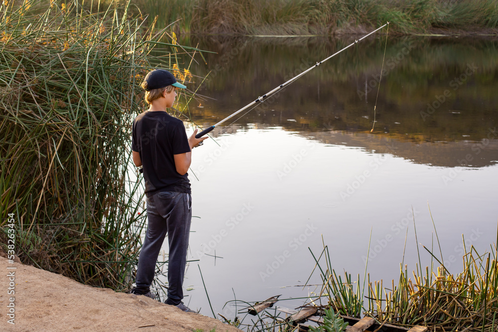 Boy fishing at the pond in the evening Boy fishing at the pond in the evening