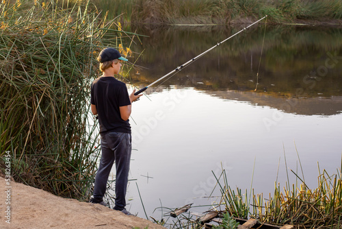 Boy fishing at the pond in the evening