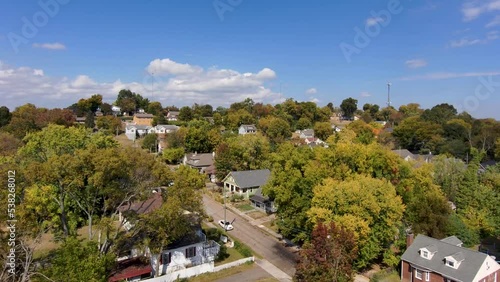 aerial footage of a gorgeous autumn landscape in the city with red brick buildings surrounded by autumn trees and lush green trees with cars parked and driving on the street in Knoxville Tennessee USA photo