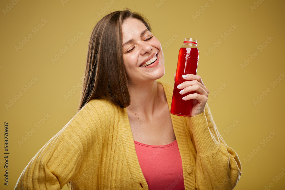 Smiling woman holding bottle with red juice drink. Isolated advertising portrait on yellow. Smiling woman holding bottle with red juice drink. Isolated advertising portrait on yellow.