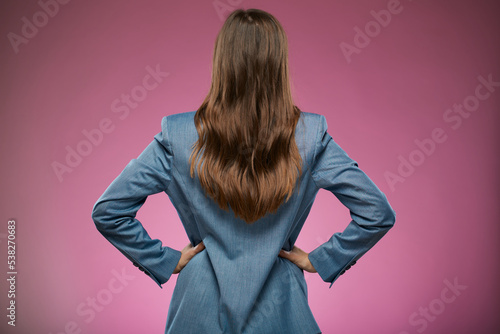 Woman in oversize jacket standing back with hands on waist. Isolated advertising portrait on pink back. photo