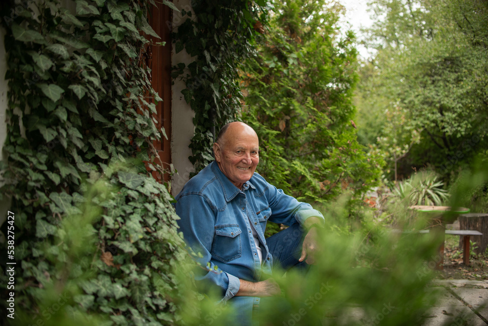 Portrait of a smiling aged man against the background of green leaves, who looks at the camera. High quality photo Portrait of a smiling aged man against the background of green leaves, who looks at the camera. High quality photo
