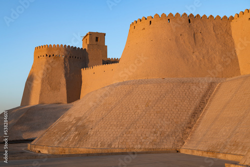 Walls and bastion of the ancient fortress Kuhna Ark in the light of the evening sun. Khiva, Uzbekistan photo