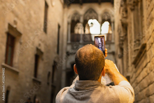 Photography Latin man taking a picture on the bridge of the bisbe in Barcelona (Spain), vacation concept