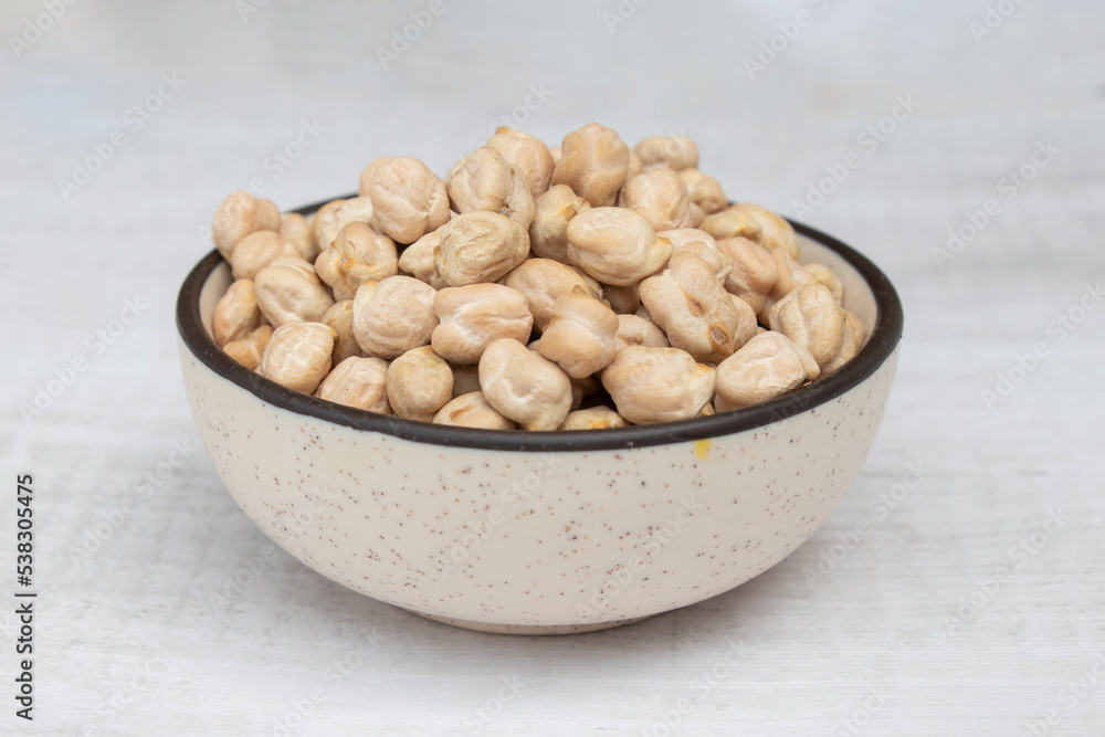 Chickpeas (garbanzo bean) in a ceramic bowl, isolated on white background, close up view