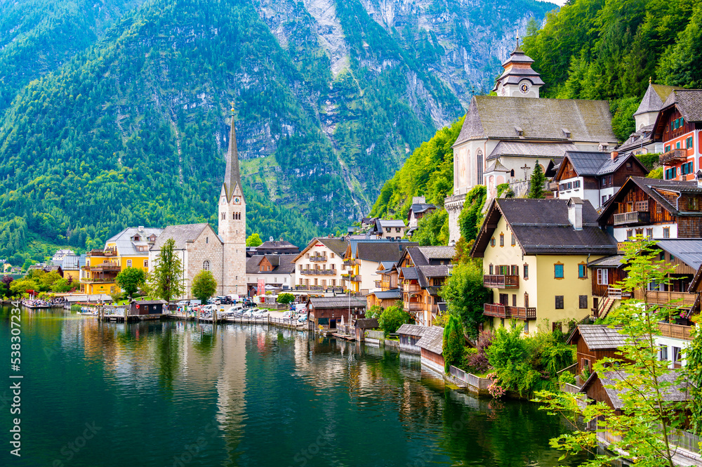 Famous view of Hallstatt city and church near the lake. Mountains in the background. Summer rainy day, soft colors, cloudy weather.