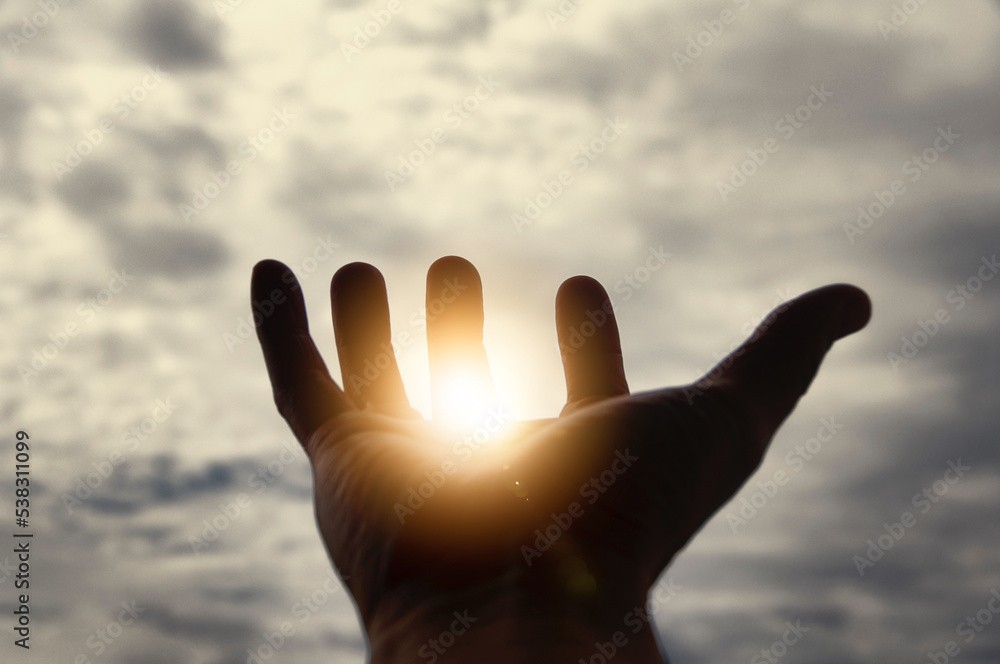 Light shining on hand with vintage sky color background. Copy space.