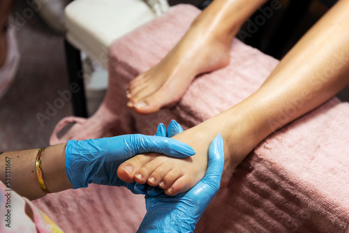 detail of a woman's foot receiving a relaxing massage during a pedicure treatment in the beauty salon, wellness and body care concept