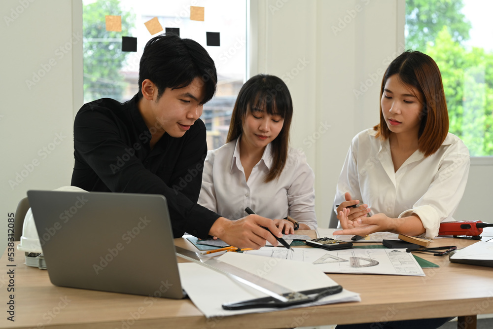 Professional team of architects brainstorming, working together on new project and building sketches in modern office Professional team of architects brainstorming, working together on new project and building sketches in modern office