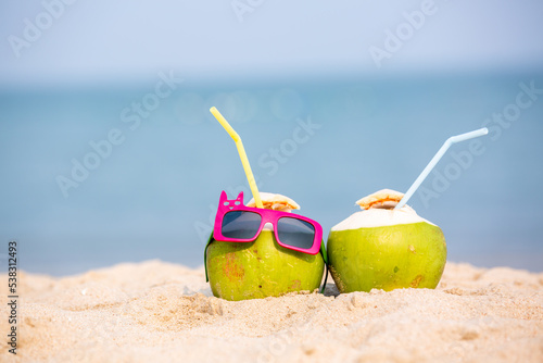 Tropical summer vacation family holiday, Coconut wearing stylish sunglasses on the sand beach with sea background, Sunny day on the beach tropical island, summer tropical pineapple.