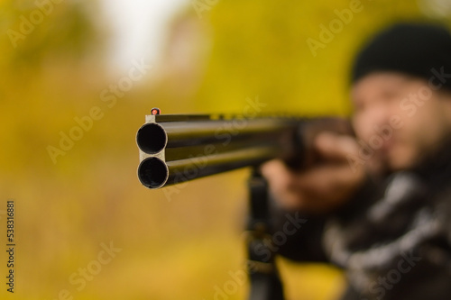 Photography Selective focus of the hands of a man in a camouflage protective suit who loads a double-barreled shotgun