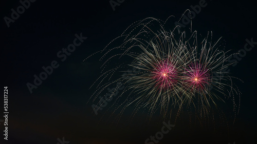 Close up of fireworks explosion with pink stars and yellow fountains. Isolated on black night sky. Ideal for Sylvester and New Year.