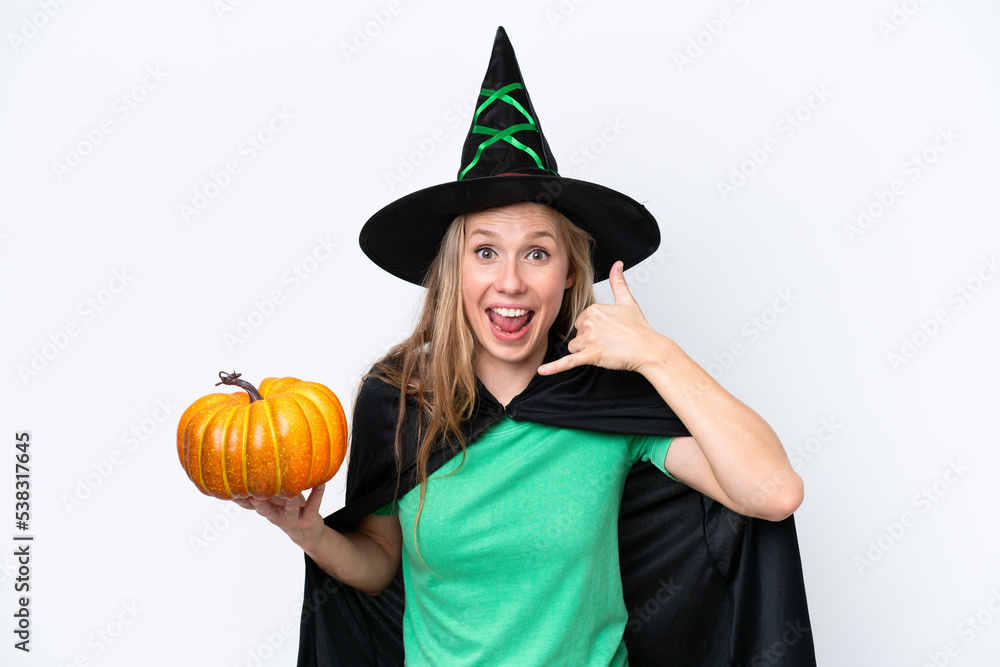 Young blonde woman dressed as a witch holding a pumpkin isolated on white background making phone gesture. Call me back sign Young blonde woman dressed as a witch holding a pumpkin isolated on white background making phone gesture. Call me back sign