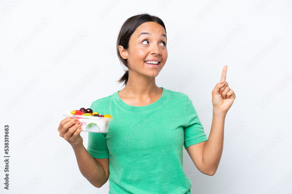 Young hispanic woman holding a bowl of fruit isolated on white background pointing up a great idea Young hispanic woman holding a bowl of fruit isolated on white background pointing up a great idea