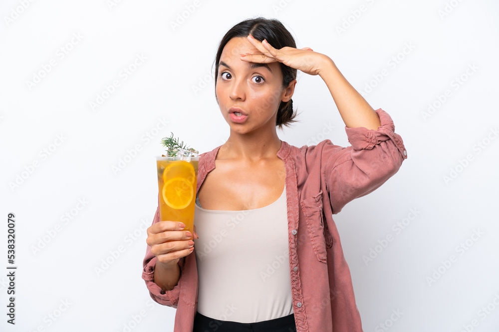 Young hispanic woman holding a cocktail isolated on white background doing surprise gesture while looking to the side Young hispanic woman holding a cocktail isolated on white background doing surprise gesture while looking to the side