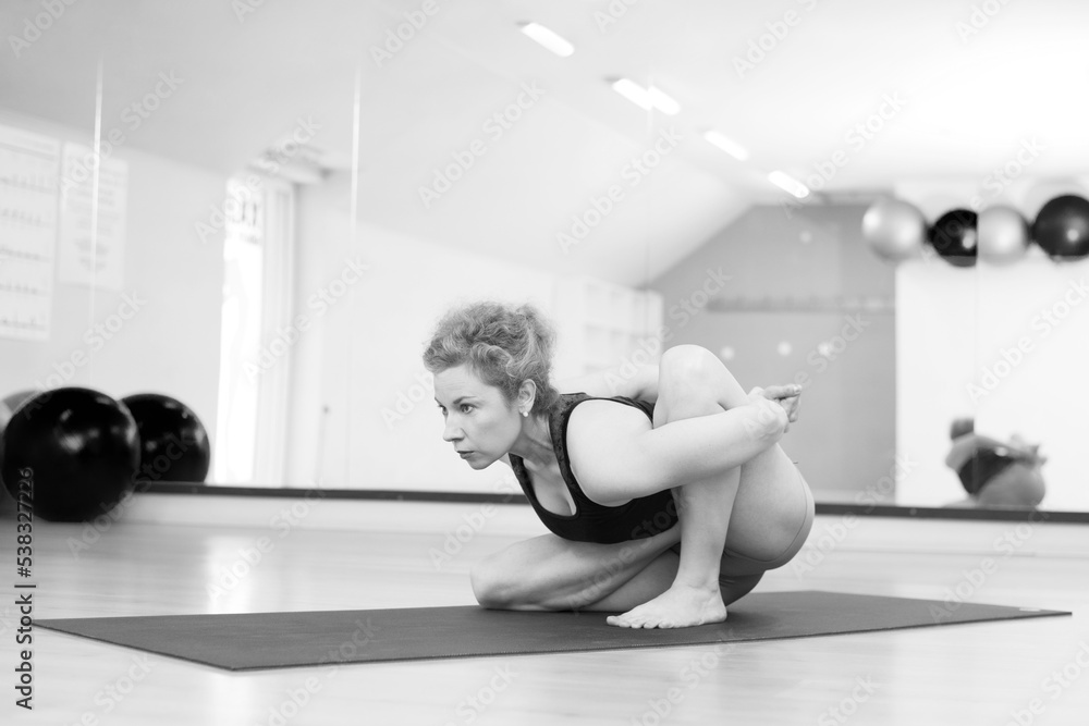 Fototapeta premium Young woman doing yoga exercise in the yoga studio