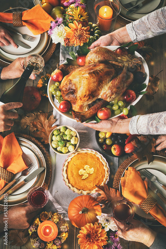 Group of friends or family celebrating together at festive turkey dinner table. Thanksgiving celebration traditional dinner concept