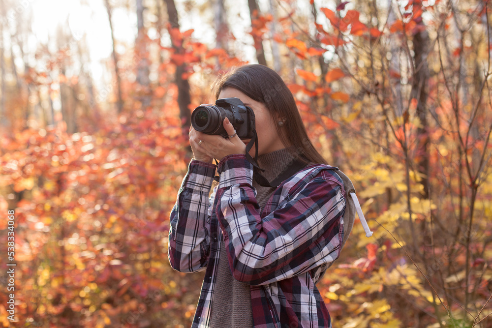 Young woman taking photos on DSLR camera in autumn forest Young woman taking photos on DSLR camera in autumn forest