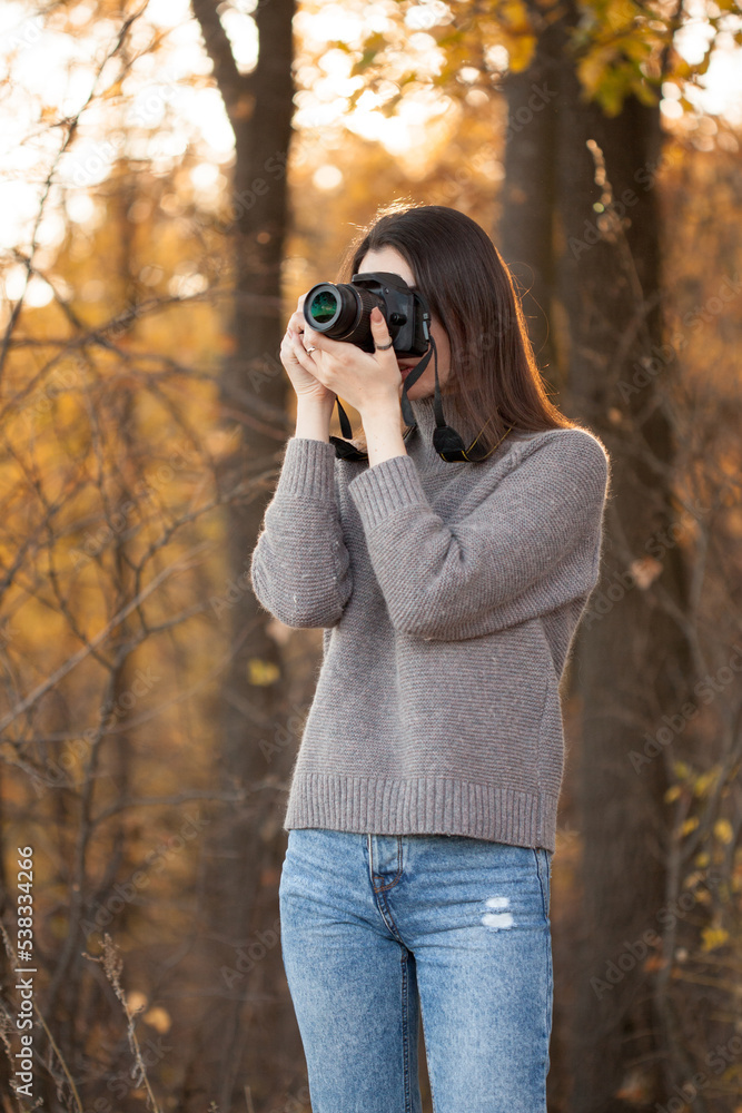 Young woman taking pictures in autumn forest