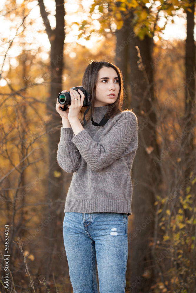 Young woman standing in forest with dslr camera Young woman standing in forest with dslr camera