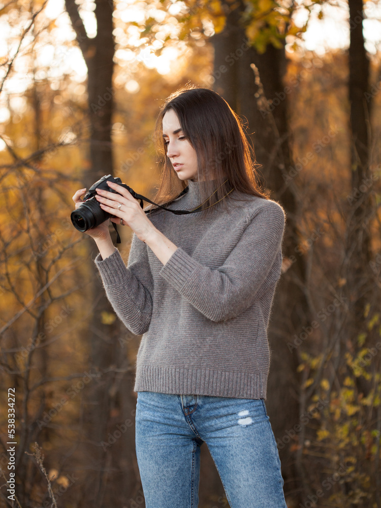 Young woman walking in forest with dslr camera